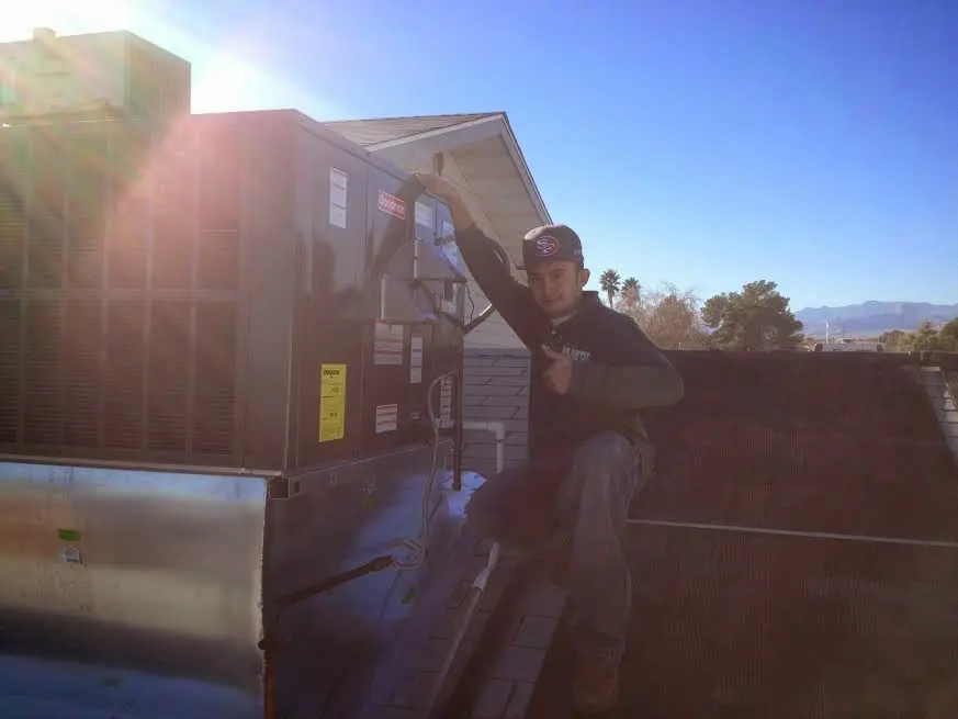 HVAC technician performing AC Tune-Up on a rooftop unit in Oakley